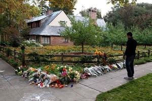 Photo: Beck Diefenbach/Reuters/Los Angeles Times -- A visitor surveys the flowers, candles and apples left outside the home of Steve Jobs in Palo Alto, CA  10/06/11